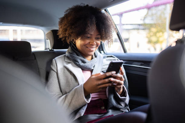Passagère souriante consultant l'application Talia à bord de son taxi